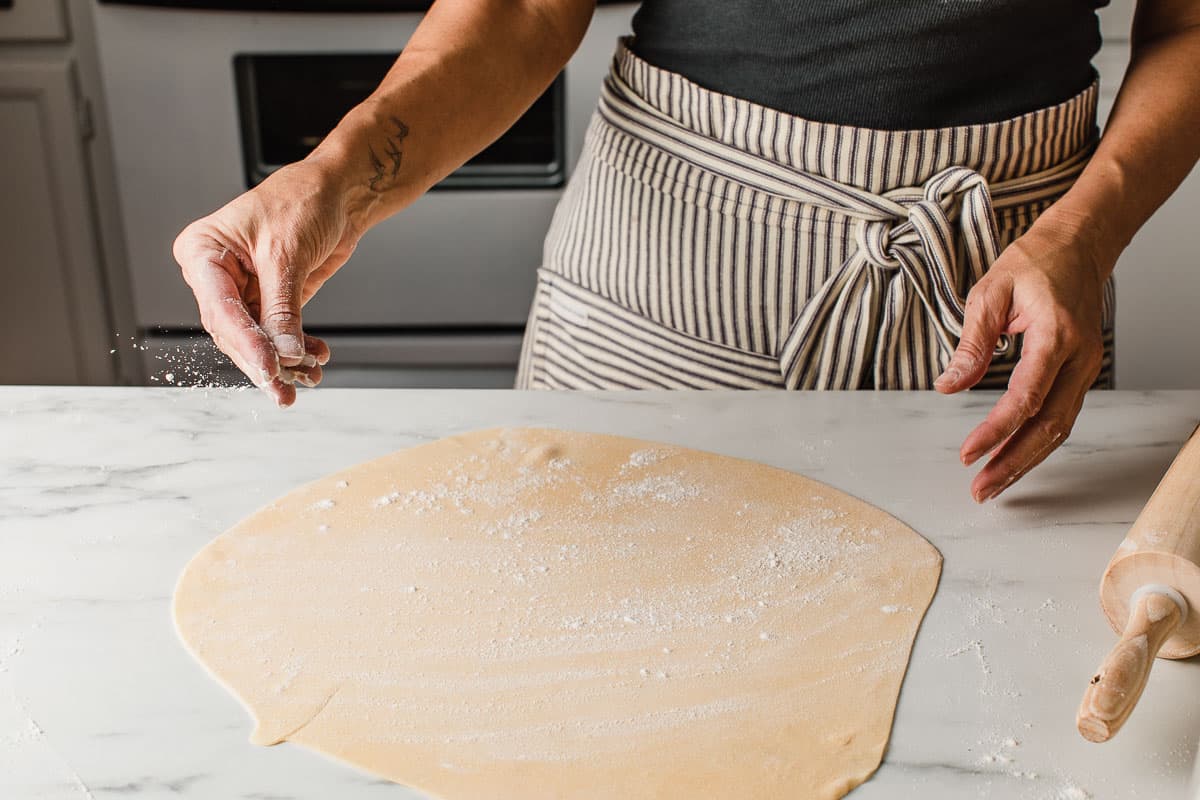 A woman flouring sourdough pasta dough.