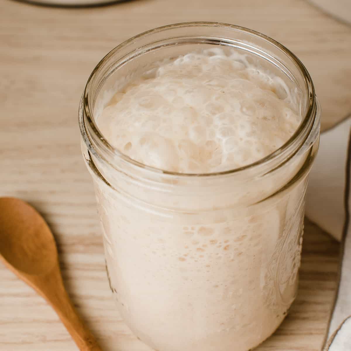 Bubbly active sourdough starter in a mason jar on the counter.