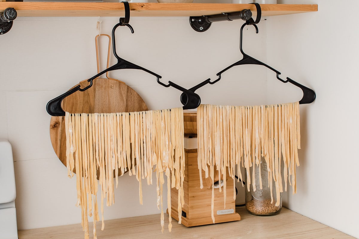 Sourdough pasta hanging to dry on hangers.