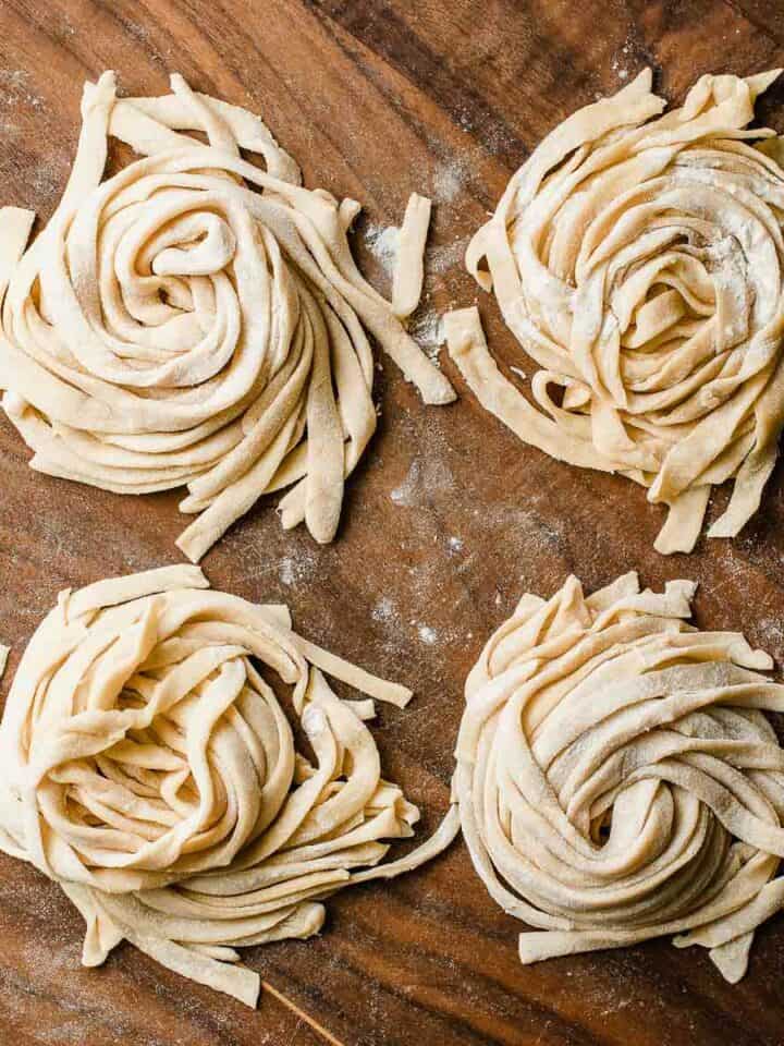 Four piles of fresh sourdough pasta on a cutting board.