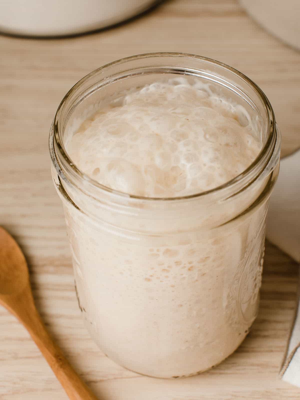 A jar of active sourdough starter resting on a kitchen counter.