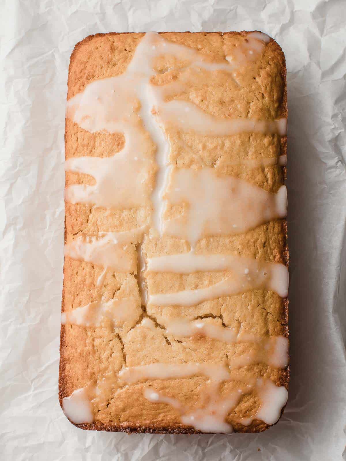 Sourdough lemon cake with lemon glaze on a sheet of parchment paper.