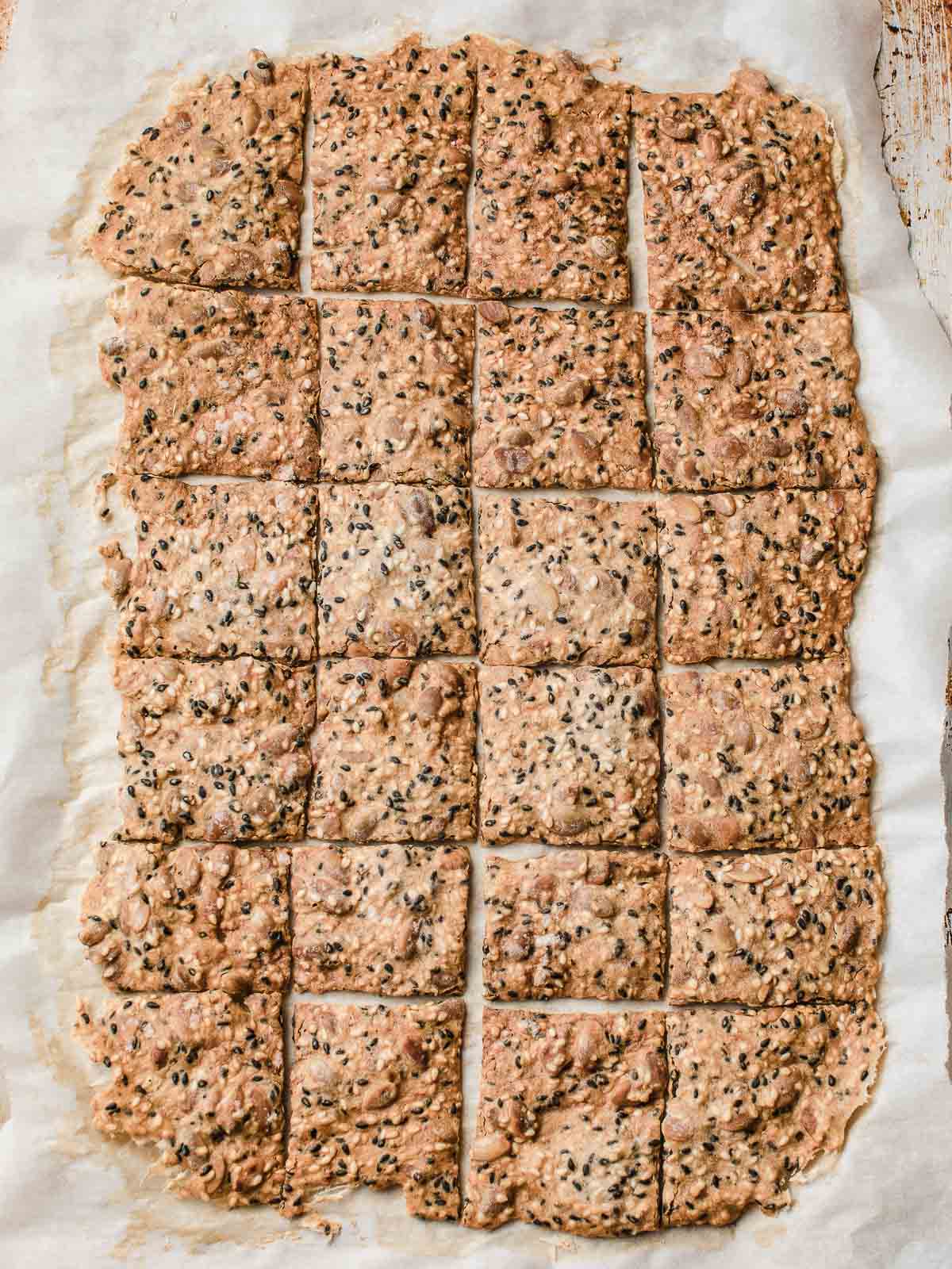 Baked sourdough seed crackers on parchment paper.