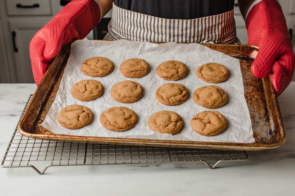 A woman holding a tray of baked sourdough ginger molasses cookies