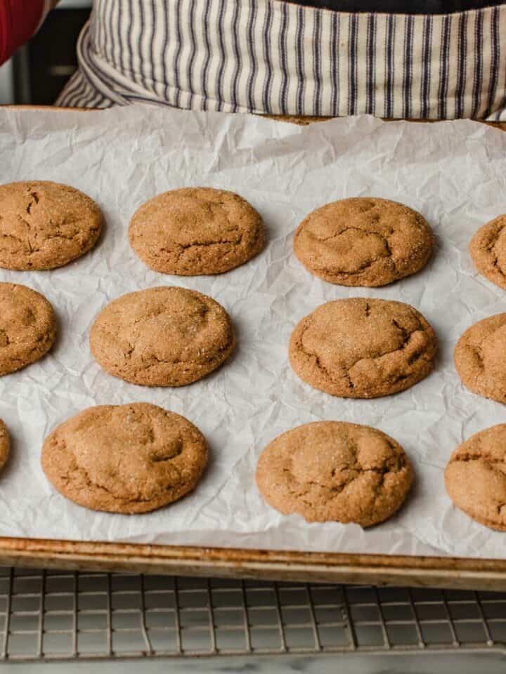 A woman holding a tray of baked sourdough ginger molasses cookies.