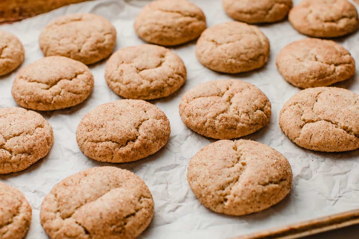 Baked sourdough snickerdoodle cookies cooling on parchment paper.