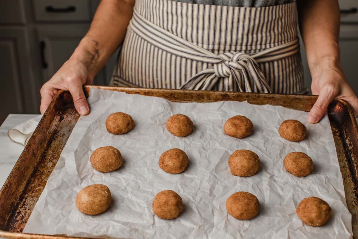 Sourdough snickerdoodle cookie dough balls on a baking sheet.