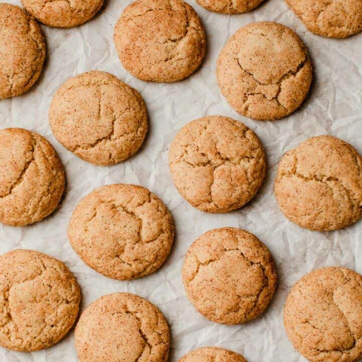 Sourdough snickerdoodle cookies on a baking sheet with parchment paper.