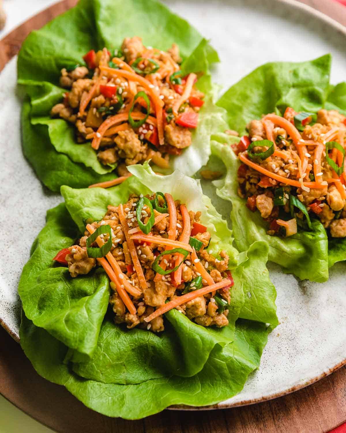 Closeup photo of 3 chicken lettuce wraps on a plate.