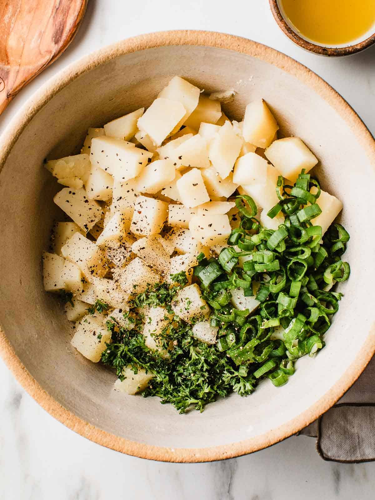 Cut potatoes and herbs in a bowl.