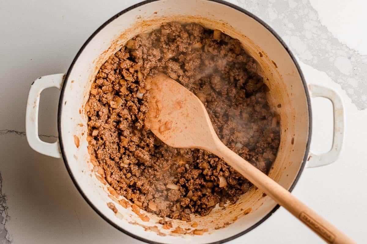 Beef browning with onions in a pot for Cheeseburger  casserole.