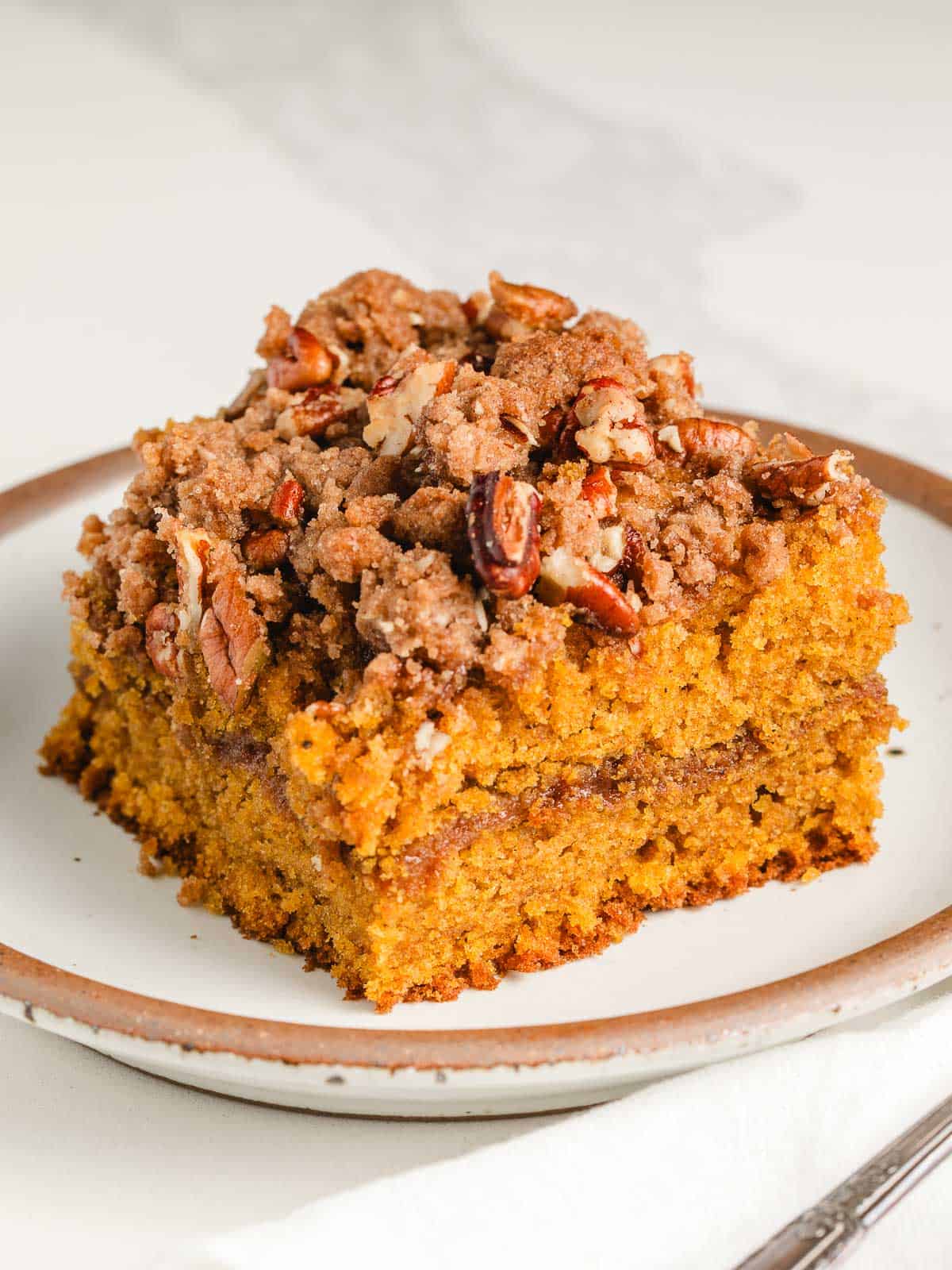 A slice of sourdough pumpkin coffee cake on a plate with a fork.