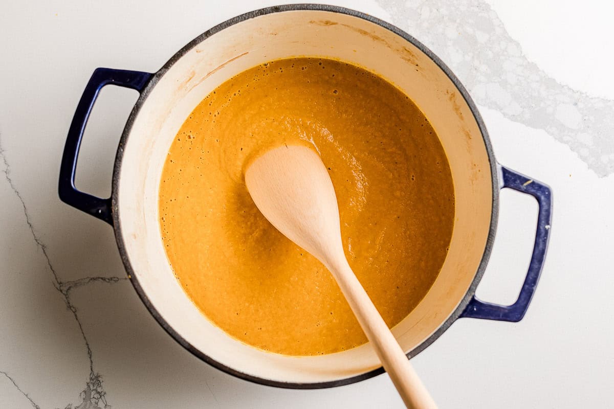 Blended pumpkin soup in a soup pot on a table.