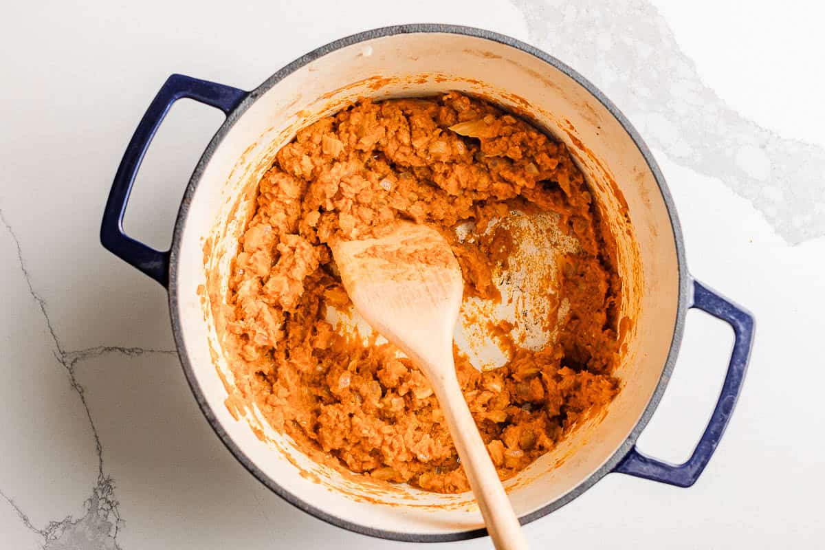 Pumpkin puree, onions, and garlic cooking in a soup pot.
