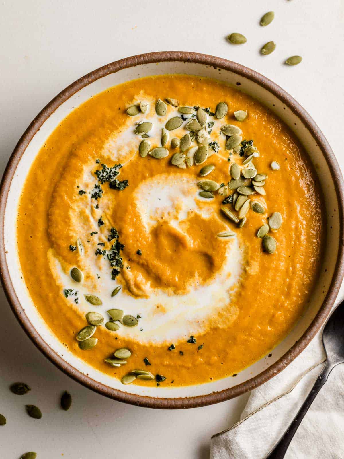 Pumpkin soup in a bowl with a spoon and napkin.