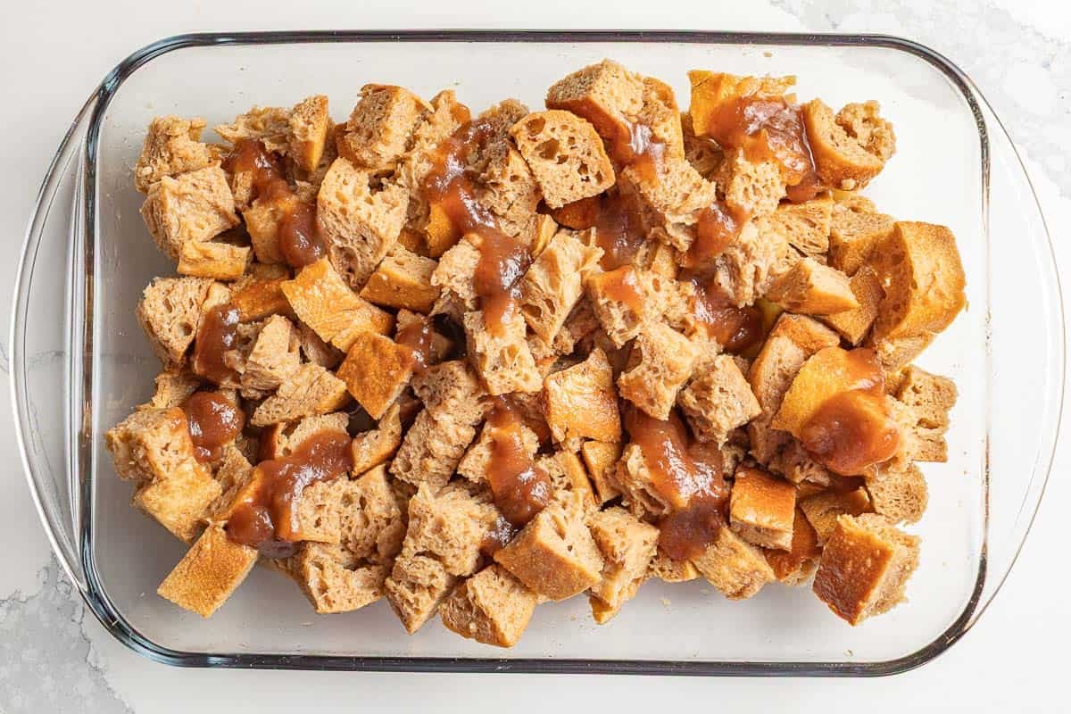 Apple butter drizzled over sourdough cube mixture in a casserole dish.