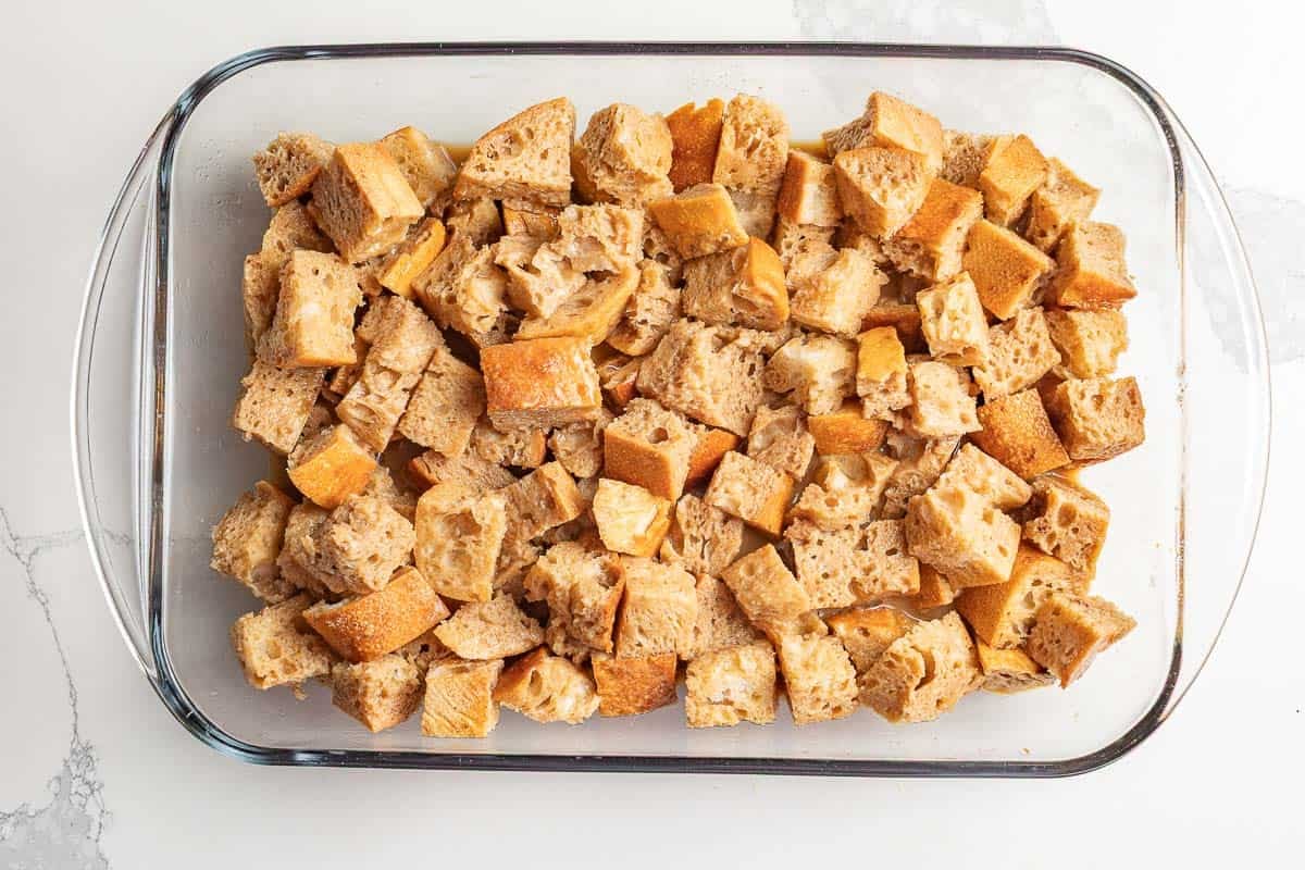 Wet ingredients poured over sourdough cubes in a casserole dish.