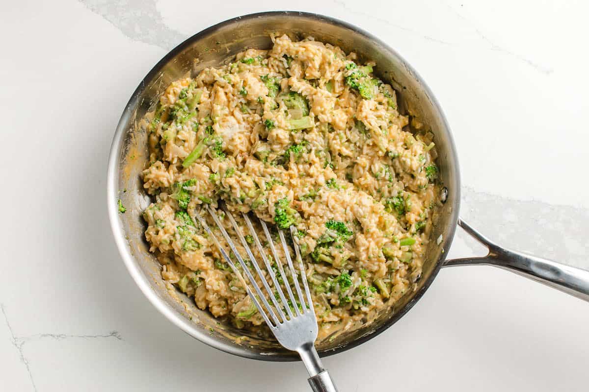 Broccoli rice casserole ingredients mixed together in a pan.
