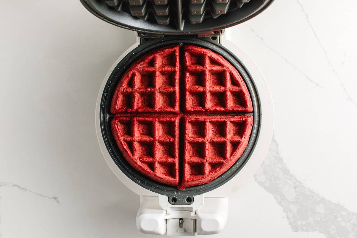 Cooked sourdough red velvet waffle in a waffle maker.