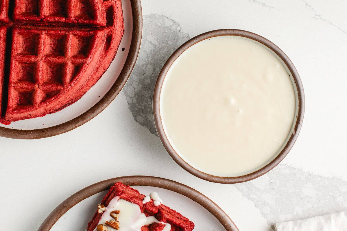 Cream cheese glaze for sourdough red velvet waffles in a bowl.