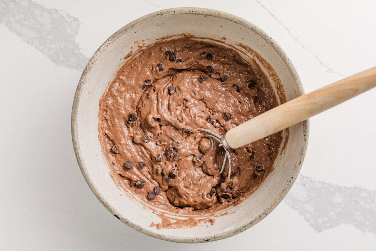 Chocolate sourdough waffles batter in a bowl with chocolate chips added.