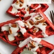 sourdough red velvet waffles on a plate with cream cheese glaze drizzled on top.