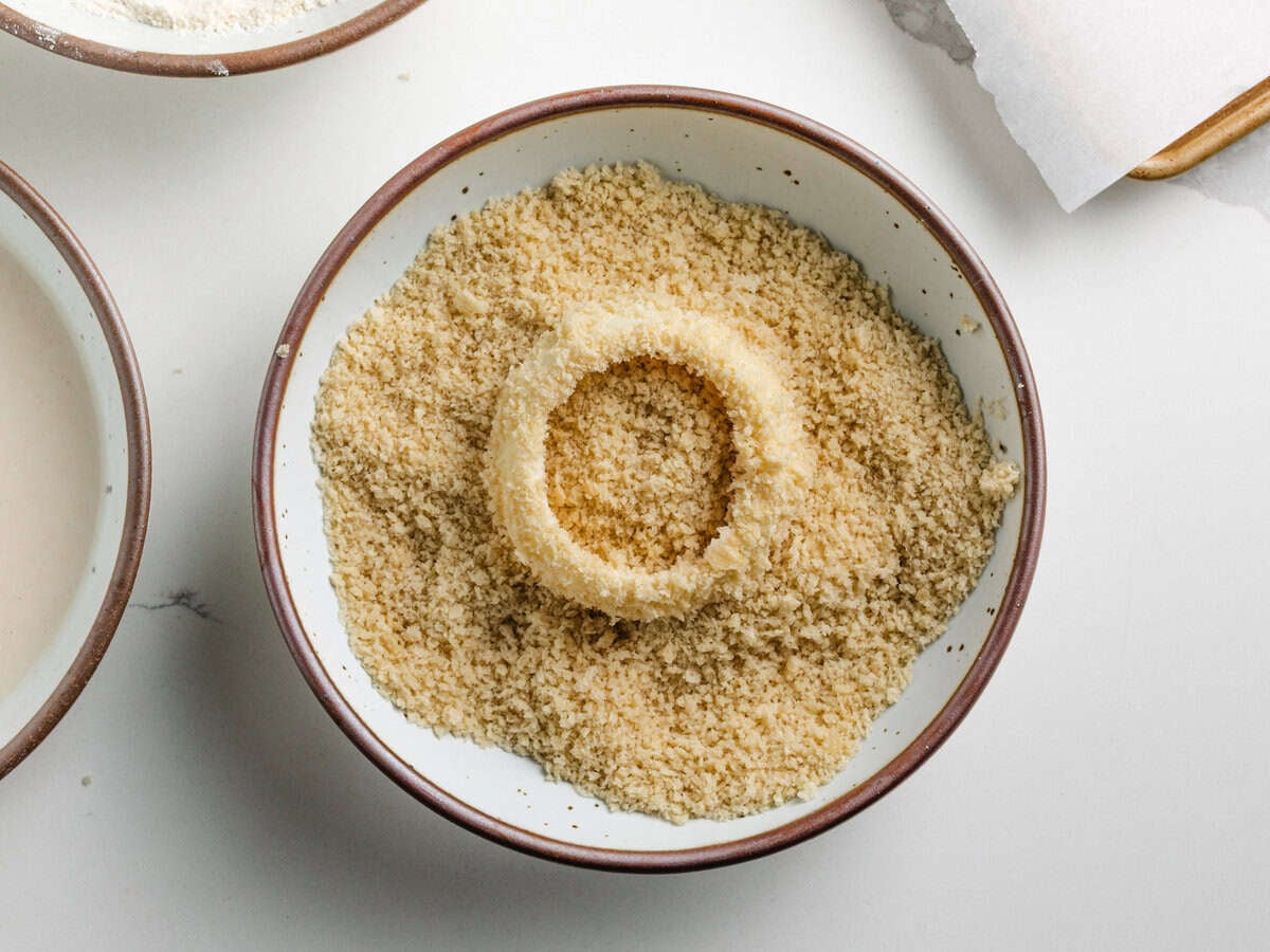 Covering an onion ring with panko breadcrumbs.