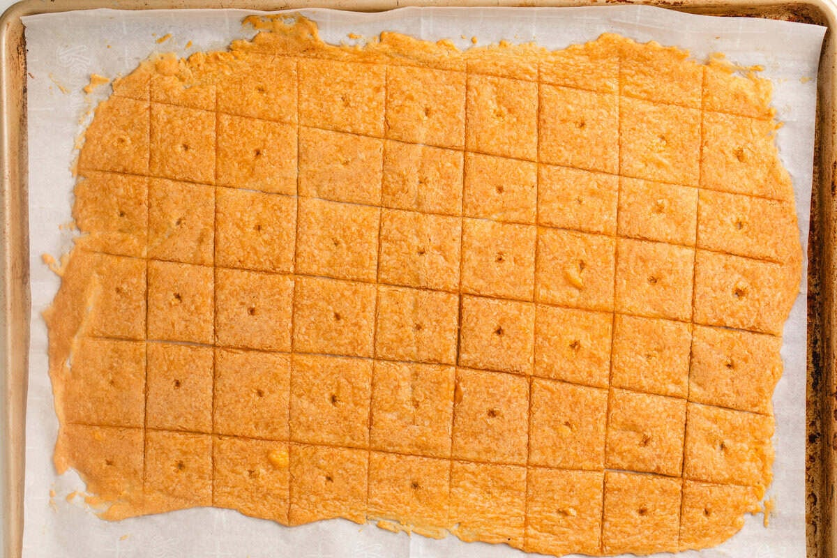 Half baked sourdough cheeze-its on a baking sheet.