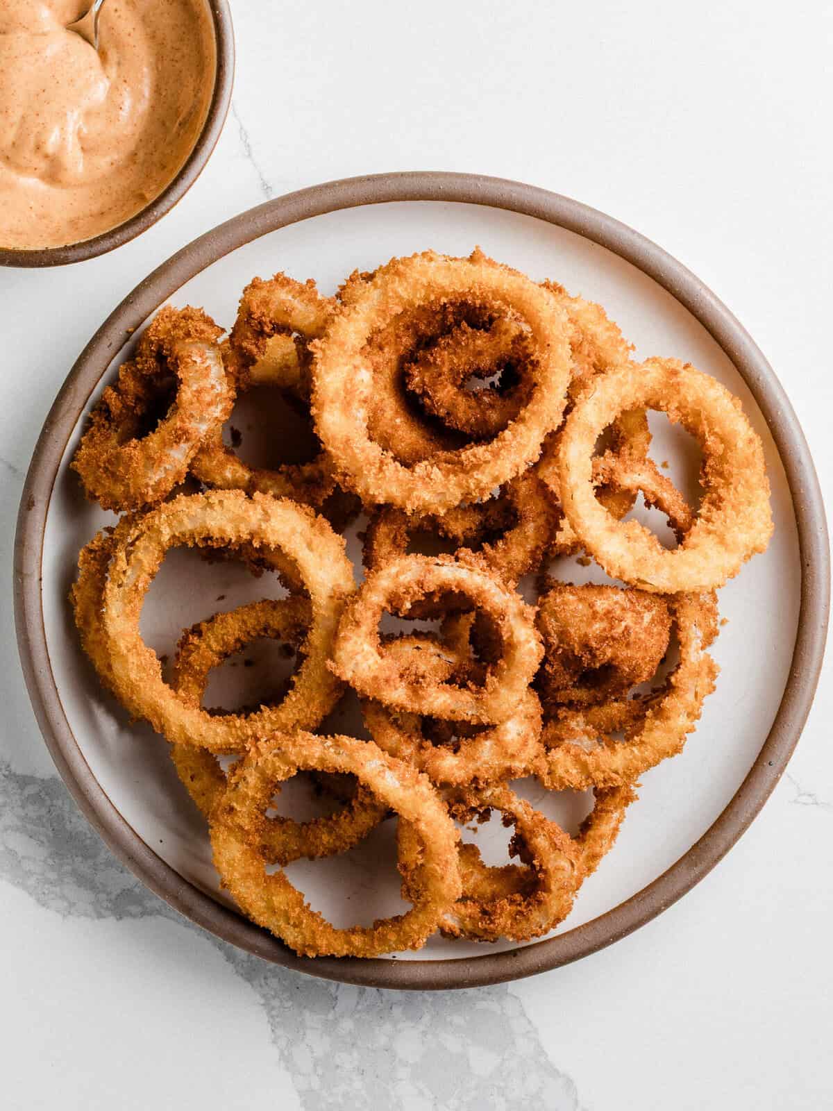 Sourdough onion rings on a plate with a side sauce.