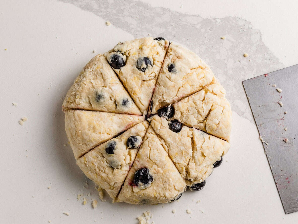 A disk of sourdough lemon blueberry dough cut into wedges on a table.