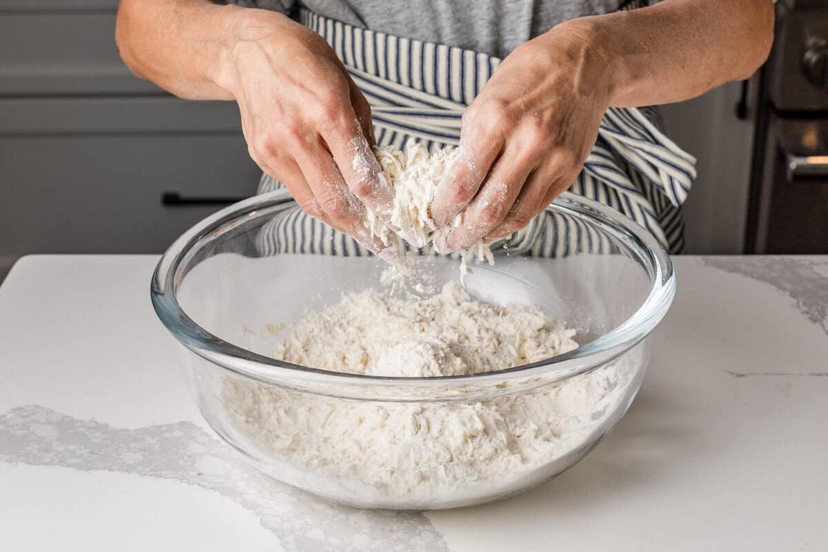 A woman mixing butter and flour together in a bowl.