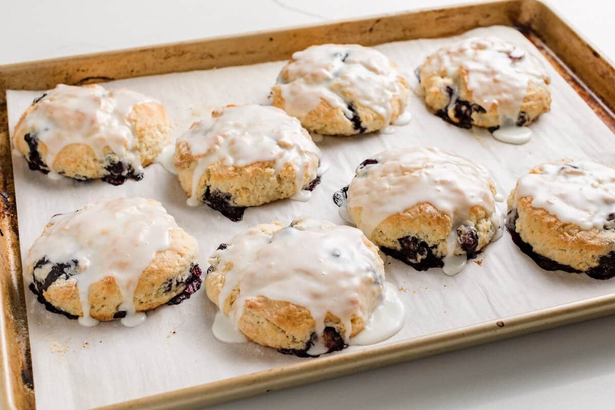 Sourdough Blueberry Biscuits with glaze on a baking sheet.